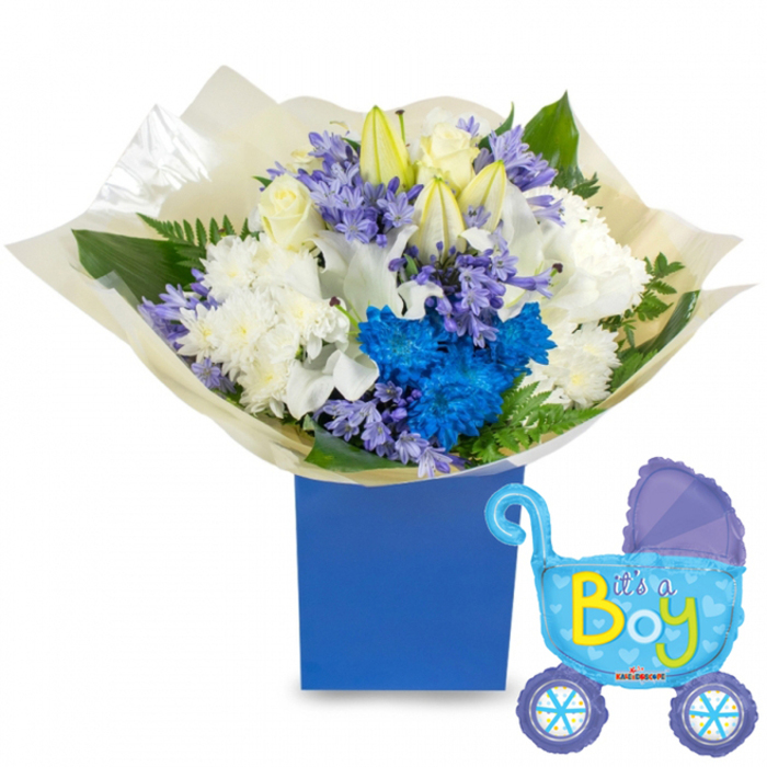 This image captures a celebratory, professionally styled bouquet created for the arrival of a baby boy, photographed against a clean white backdrop to emphasise colour and form. The arrangement is densely packed and rounded, planted in a robust royal-blue presentation box that anchors the composition with a cool, dependable tone. Dominant white elements-velvety roses, partially unfurled white lilies with soft yellow stamens, and voluminous chrysanthemums-compose a serene core, their textures ranging from the satin-smooth rose petals to the feathery chrysanthemum heads. Interwoven among these are vivid electric-blue chrysanthemums and smaller periwinkle or lavender-blue florets, likely hyacinth-like clusters, which lend sculptural depth and a bright, celebratory pop. Sprigs of fresh green foliage, including broad leaves and delicate fern fronds, provide contrast and movement, their glossy surfaces reflecting a gentle studio light. The base is wrapped in translucent cream-coloured tissue, slightly crinkled, adding an artisanal finishing touch and a tactile invitation to unwrap. To the right, a light-blue foil balloon in the shape of a baby carriage tilts into view, detailed with darker-blue canopy accents, patterned wheels and tiny hearts; the carriage proclaims It's a Boy in cheerful yellow-green lettering. The overall mood is joyful and composed-ideal for delivering to new parents in Queensbury, for display at a local baby shower on Kingsbury Road, or for same-day hand delivery to nearby family addresses-combining clear design intent with approachable, fresh fragrance and timeless blue-and-white elegance.