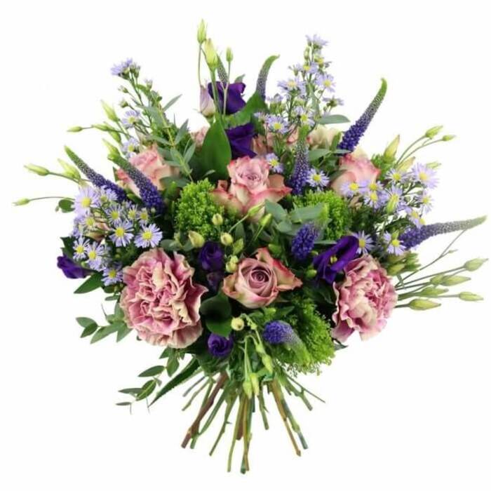 This image shows a generous, dome-shaped hand-tied bouquet resting against a crisp white background, every detail sharply defined as though freshly arranged in a Queensbury florist's studio that morning. The dominant impression is of soft pinks and purples layered with refreshing greens. At the core, several large roses unfold in shades of blush and mauve-pink, some in tighter buds and others more open, with petals that shift from deeper, warm centres to paler, almost cream-tinted edges. Interlaced with them are plush carnations in dusty rose and muted mauve, their many ruffled petals adding a sense of depth and romantic opulence. Piercing this rounded mass are upright, tapering spires of Veronica in deep violet-blue, their textured florets stacked along slim stems that create a vertical rhythm and draw the eye upward, like flower spikes you might notice in a Queensbury front garden near Stag Lane. Around and between these focal blooms, smaller starry asters and similar daisy-like flowers in lavender and periwinkle scatter a light, cloud-like softness, each tiny head centred with a pale yellow eye. Deeper tones of purple appear in scattered lisianthus blooms, their gently flared, bell-shaped petals providing contrast and a touch of drama. The whole design is cradled in vibrant greenery: broad, silvery eucalyptus leaves curve elegantly around the edges, while clusters of almost chartreuse-green textural filler punch bright notes of fresh colour through the arrangement. At the base, a tight bundle of clean, green stems is clearly visible, bound neatly in classic hand-tied fashion, ready to slip into a vase in a Queensbury living room or dining space. The bouquet feels luxurious yet welcoming, ideal for marking an important birthday, commemorating a wedding anniversary, or sending a heartfelt message of care and appreciation to someone local.