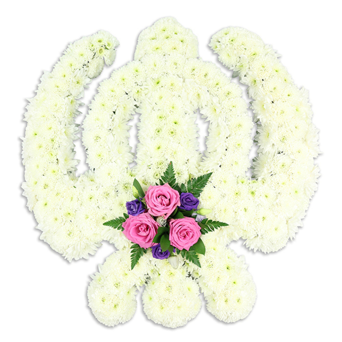 A beautifully composed Khanda floral tribute, designed in the revered symbol of Sikhism, appears almost sculptural against a spotless white background. The entire emblem-the central double-edged sword, the surrounding circular chakkar, and the two outward-curving kirpans-is crafted from a dense mass of white chrysanthemums, each bloom carefully set so that no gaps break the smooth, continuous surface. The petals, slightly curled and feathery at the edges, catch the light in subtle ways, creating gentle shadows and highlights that define the sacred contours. This gives the impression of a soft yet strong structure, like a cushion of purity honouring a cherished life. At the lower centre of the design, cradled by the crossed kirpans, sits a small but vivid focal cluster. Three pink roses, fresh and full, open gracefully toward the viewer, their spiralled petals adding a sense of tenderness. They are surrounded by a ring of deep purple or violet flowers, their smaller trumpets and petals bringing texture and contrast, while glossy green fern fronds and foliage extend gently beyond, softening the lines and adding a natural rhythm. The colour placement feels deliberate and respectful, ensuring the Khanda's shape remains dominant while the accent blooms hint at personal love and remembrance. The composition is ideal for Sikh funeral services and memorials in Queensbury and the surrounding neighbourhoods, from quiet side streets off Queensbury Circle to family homes near Stag Lane. Crafted with the care of local florists who understand both floral design and Sikh traditions, this tribute offers a serene, dignified expression of faith, gratitude, and eternal remembrance.