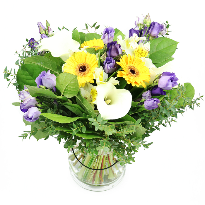 An artfully hand-tied mix of bright yellow Gerbera daisies, pristine white Calla lilies, and soft lavender Lisianthus forms a generous, naturally curved bouquet. Set in a clear glass cylindrical vase, the stems are neatly trimmed and visible through the water, giving a clean, garden-fresh look against a white backdrop. The daisies anchor the arrangement with sunny cheer, their centers deep and dramatic, while the Calla lilies add sleek, architectural lines that contrast with the Lisianthus' lilac haze. Layered among them are clusters of lilac and white Lisianthus in varying stages of bloom, some fully open with ruffled petals, and others poised as buds, adding depth and a sense of movement. White Alstroemeria whisper through the composition, their subtle yellow markings catching light as they unfurl. The greenery-silvery eucalyptus and broad green leaves-provides volume, texture, and a fragrant, fresh counterpoint to the blooms. Presented in Queensbury's local hands, the arrangement exudes warmth and refined joy, a versatile choice for celebrations, home decor, or thoughtful gifts. The bouquet's clean glass vase makes it easy to place on a dining table or mantel, where it invites the eye to linger and the room to feel brighter. Available for same-day delivery across Queensbury and surrounding areas through Flower Delivery Queensbury.