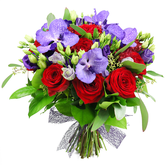 An opulent hand tied bouquet rises against a white backdrop in Queensbury, a refined blend of red and purple that speaks of passion and elegance. The fully opened red roses stand proud, their velvety layers catching the light, while purple Vanda orchids spread their broad, flat petals with a speckled finish that signals luxury. Between and around them, clusters of lisianthus in soft lilac soften the contrast and add delicate movement. The arrangement is framed by lush green foliage, from glossy broad leaves to slender sprigs that give volume and depth, with fresh green buds tucked in to invite the eye onward. The stems are gathered at the base and finished with a dark plum mesh ribbon that forms a textured bow, contemporary yet timeless.

This bouquet feels designed for celebrations, whether a milestone anniversary, a festive dinner party, or a grand thank you. Its colour story-rich reds, regal purples, and verdant greens-recalls the twilight hours over Queensbury's leafy streets and the warmth of a home prepared for guests. Freshness is assured by careful sourcing and daily delivery, with same-day service available across Queensbury and nearby districts, making this gift ready to delight a recipient from the High Street to nearby Edgware Road.