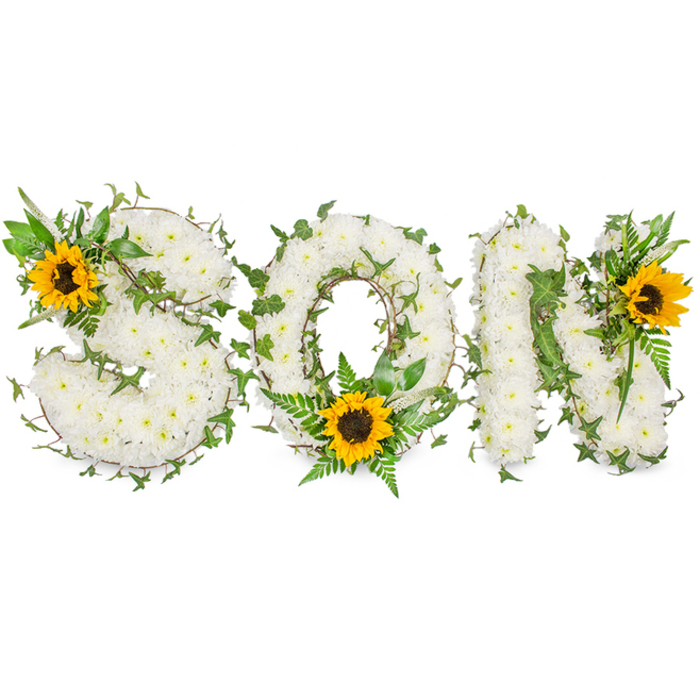 A carefully composed funeral tribute spells SON in substantial, capital letters, each letter densely covered with tiny, immaculate white chrysanthemums that form a feather-soft, tactile surface. The white chrysanthemums are compact and even, giving the letters a sculpted, cloud-like quality that feels both tender and dignified. Intertwined through the floral base are trailing strands of dark green ivy; their twisting stems and glossy leaves trace gentle curves around the letters, providing a natural framework and a sense of continuity and memory. Sprigs of lighter green fern fronds and assorted pointed leaves emerge here and there, adding contrast and a whisper of woodland freshness beneath the white bloom. Punctuating the composition are three striking sunflowers-bold yellow petals radiating from rich, dark brown centres-deliberately placed to draw the eye: a sunflower sits at the S's upper-left arc, another cradles the lower curve of the O among the ferns, and the final bloom crowns the N's upper-right angle. The juxtaposition of pure white, deep greens, and golden yellow creates an emotional balance-solace and warmth together-suitable for a memorial service or graveside tribute. Set against a stark white studio background with soft, even lighting, every petal, vein and texture is visible; the image reads like a quiet, assured statement of love and remembrance for a son, made with florist's care and floral craftsmanship familiar to families across Queensbury and nearby streets like Honeypot Lane and local green spaces.
