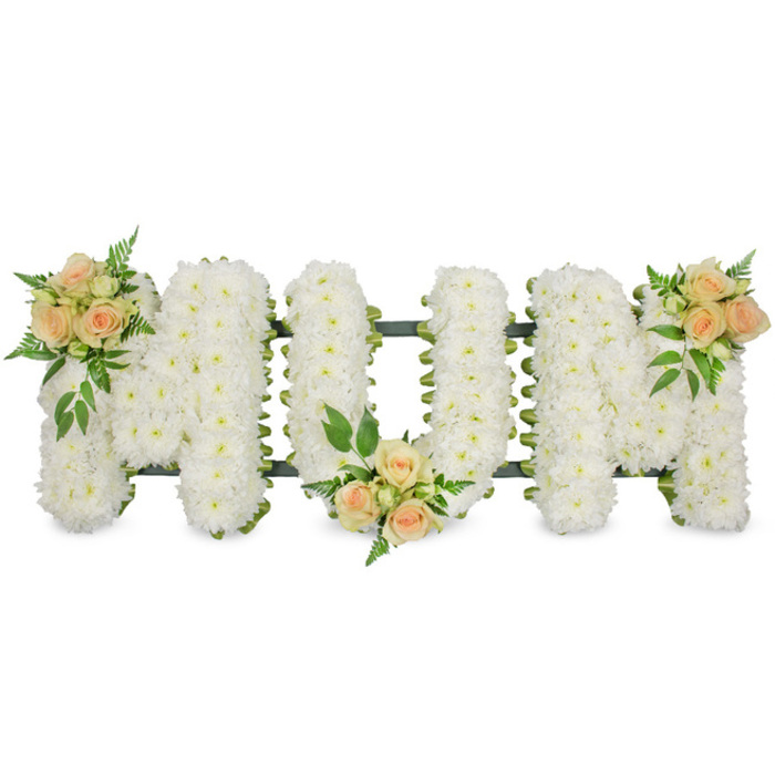 This poignant floral arrangement presents the word MUM in strong, uppercase letters, laid out horizontally against a clean white background that allows every detail and nuance of the design to stand out. Each letter is completely filled with pristine white spray chrysanthemums, placed tightly together so that they form a smooth yet softly textured surface, like a gentle cushion of petals. The chrysanthemums' small, rounded blooms create a uniform field of white, symbolising purity, respect, and the tender side of grief. Around the edges of the letters, a discreet dark green structural frame or ribbon peeks through, giving definition and subtle contrast without disturbing the calm atmosphere of the piece. To bring warmth and a personal touch, three clusters of roses in soft peach and delicate blush pink are carefully positioned: one bouquet rests at the top left of the first M, another nestles at the lower centre curve of the U, and the third sits at the top right of the final M. Each cluster combines larger open roses with smaller buds, suggesting the different chapters of a mother's life and the memories held by her family. The roses are surrounded by varied greenery, from feathery ferns to simple, deeper green leaves, which add structure, movement, and a natural garden feel. Overall, the tribute conveys quiet love and gratitude, the kind of bespoke funeral lettering families in Queensbury might choose when arranging flowers for a cremation or memorial ceremony close to the station or along Honeypot Lane, wishing to honour a mother with grace and understated beauty.