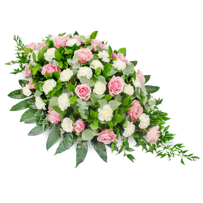This image shows a beautifully crafted funeral spray, styled in a classic elongated teardrop form and placed against a crisp white backdrop so every detail of the flowers can be clearly imagined. The arrangement is fullest at the upper left, where a lush cluster of blooms gathers together, then gently narrows as it moves to the lower right, ending in a tapered point that suggests the graceful fall of a single tear. The main flowers are soft pink roses in varying stages of bloom, from tightly curled buds to fully open blossoms with layered, velvety petals spiralling outwards. Interwoven among the roses are generous clusters of fluffy white carnations, their ruffled petals catching the light and offering a tender contrast to the sleek rose heads. Surrounding this pastel harmony is a rich frame of foliage: deep, glossy green leaves likely from salal give solid structure, while rounded, silvery eucalyptus leaves introduce a softer, muted tone that feels almost soothing to the eye. Delicate strands of trailing ruscus extend from the slimmer end of the spray, creating a natural, cascading movement that softens the overall outline. The lighting is even and gentle, so the pinks and whites appear tranquil and pure, making this arrangement a fitting tribute for a memorial service in Queensbury, whether placed beside a casket or as a standalone condolence spray. It evokes the quiet, reflective atmosphere of an early morning walk through the neighbourhood, and reflects the kind of thoughtful artistry a local florist would provide when helping families express sympathy, remembrance, and enduring affection.