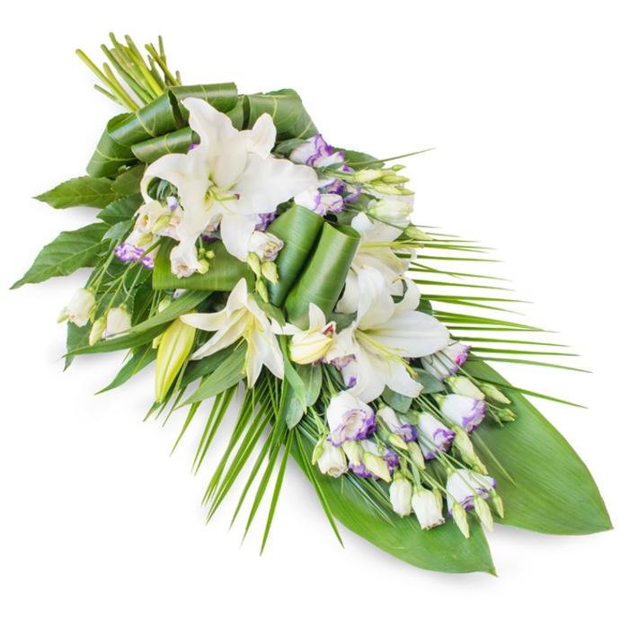 Against a spotless white backdrop, a refined, teardrop-shaped sympathy spray stretches gracefully on the diagonal, its form widening near the top and narrowing to a gentle point below. At the centre are several striking white oriental lilies, their large, recurved petals creating soft arcs that draw the gaze inward. Some lilies are fully open, showing pale golden stamens dusted with pollen, while others remain in partially opened bud, evoking the tender fragility of memory and the promise of peace. Interlaced with them are stems of white lisianthus, each small, bell-like flower edged and veined with a hint of lavender, providing a subtle contrast that never overwhelms the calm mood. Tightly closed lisianthus buds punctuate the design like pauses in a quiet conversation, adding depth and interest from every angle. The flowers rest on a generous foundation of greenery: broad, dark green leaves possibly from tropical foliage plants are layered to form a rich base, some folded or rolled into contemporary shapes that speak to the florist's artistry. Long, narrow palm fronds emerge from one side and sweep along the length of the spray, giving the composition its sense of direction and flow, much like the steady routes that run through Queensbury towards neighbouring areas. The colour palette is restrained-ivory whites, gentle lavender touches, and multiple shades of green-creating an atmosphere of contemplation and respect. This is the sort of floral tribute that could be placed beside a coffin in a local church, at a crematorium chapel, or on a memorial table at a home gathering in Queensbury, offering loved ones a soothing focus for their thoughts and prayers.