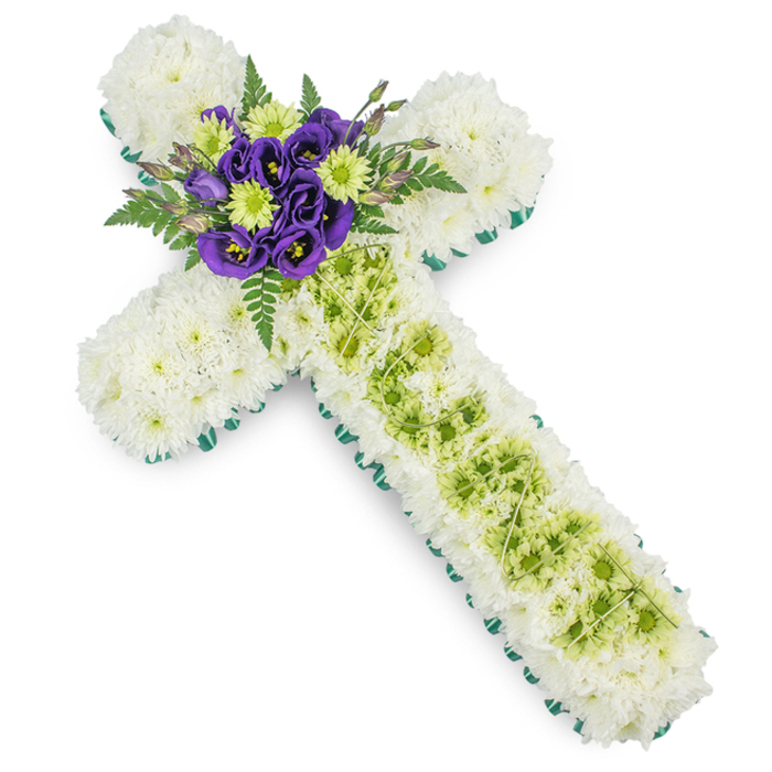 A beautifully composed funeral cross arrangement is shown from above, its details standing out sharply against a clean white background, as if prepared for a quiet chapel service in Queensbury. The entire form of the cross-both arms and stem-is meticulously padded with pure white spray chrysanthemums, each bloom set closely beside the next to form a continuous, soft-textured surface that feels calm and contemplative. Around the perimeter, a bright green band of ribbon or foliage runs in a precise line, carefully following each curve and corner so the familiar Christian shape is instantly recognisable, even at a distance. Down the centre of the vertical arm, a contrasting strip of light, lime-green button chrysanthemums or similar small blooms adds gentle colour, resembling a pathway of light leading the eye towards the centre. Over this green strip, thin, pale green decorative wires are arranged in a subtle criss-cross pattern, like a delicate net or quiet geometric lattice, lending an air of thoughtful craftsmanship. At the junction of the arms, the design blossoms into a vibrant central cluster: deep, regal purple lisianthus with ruffled, silky petals nestle among cheerful lime-green spray chrysanthemums, their fresh tones echoing the vertical panel below. Fern fronds and other dark green foliage emerge gracefully from behind, softening the edges and giving the impression of a small, living garden gathered by an experienced Queensbury florist for a farewell service. This arrangement is clearly intended as a sympathy tribute, suitable for church altars, crematorium chapels, or gravesides in and around Queensbury, expressing respect, faith, and gentle remembrance through its harmonious blend of white, green, and purple.