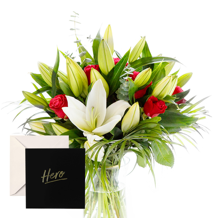 Near our Queensbury storefront, I blend the bold with the serene in this arrangement, a testament to harmony between strength and calm. White lilies drift at the heart, luminous and airy, their satin petals contrasting with a lush, forest-green backdrop of leaves. Rich ruby roses punctuate the design, each bloom a symbol of love and respect. Verdant leaves provide a cooling frame, while unopened lily buds hint at new beginnings. In soft, natural light, the bouquet feels alive and uplifting, perfect for honoring someone's strength or celebrating a major achievement. The accompanying 'Hero' card personalizes the gesture, making it intimate and enduring.

Available for delivery across Queensbury, we reach doorsteps, offices, and care homes alike, with same-day delivery to streets near the High Street and nearby parks. The contrast of crisp white and deep red, set against glossy greens, communicates courage and tenderness in equal measure. This is a timeless tribute, suitable for birthdays, promotions, or heartfelt thanks, and it travels well in a sturdy vase. The craftsmanship shows in every alignment of stem and leaf, the bouquet telling a story of admiration and resilience, a quiet homage to a local hero.
