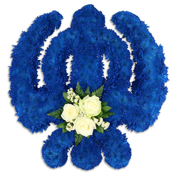 A striking Sikh Khanda floral tribute dominates the image, its iconic shape rendered entirely in a sumptuous field of royal blue blossoms. Every curve of the chakkar, every sweep of the twin kirpans, and the upright central sword are picked out with precision, giving the piece a clear, confident silhouette even from a distance. The florist has used scores of small, densely packed chrysanthemum florets, their petals layered and slightly ruffled, to build a lush, carpet-like texture. The blue tone is rich and saturated, suggesting depth and contemplation, much like the quiet moments of prayer shared in local Queensbury homes before a funeral or remembrance service. At the lower centre of the Khanda, where the swords meet, a small yet luminous arrangement of white flowers draws the eye. Three perfectly formed white roses open softly, their petals creamy and smooth, surrounded by a delicate collar of tiny white blooms and wisps of baby's breath. Pockets of dark green foliage, including glossy leaves and graceful ferns, cushion the roses, giving the composition balance and a fresh, living contrast to the intense blue. Set against a clean white backdrop, the tribute appears almost to float, with gentle shadows lending a sense of weight and craftsmanship. It feels both ceremonial and deeply personal, the kind of arrangement a Queensbury family might choose to honour a devout relative, whether placed beside a coffin, at a gurdwara near the Broadway, or at a quiet gathering after the service. The overall mood is one of solemn beauty, loyalty, and enduring faith.