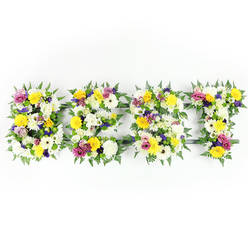 Presented on a crisp white background, the four letters forming the word BEST are crafted as a luxurious, hand-built floral statement, rich in texture and tonal contrast. Each letter is densely surfaced with a palette of sunlit yellow roses and gerbera, pure white chrysanthemum-like blooms that bring softness and volume, and dusky mauve to deep purple lisianthus that give a graceful depth to the composition. Bright fuchsia and magenta spray roses or small carnations appear throughout, their vivid tones lifting the arrangement and drawing the eye across the sculpted lettering. Between the larger blooms sit clusters of pale green and ivory fillers, tiny starry blossoms that add delicate texture and a whisper of fragrance when seen up close. Dark green fern fronds are woven around the perimeter of each letter, their lacy foliage providing a natural frame and helping to define the shapes against the stark backdrop. A discreet dark-green support frame is visible in a few narrow places, testament to the structural care required for a free-standing tribute of this scale. Shot straight-on in soft, even lighting, the arrangement reads as fresh, meticulously assembled and appropriate for commemorations or honoured celebrations. As a Queensbury florist familiar with local family services and the High Street, I imagine delivering this piece to a chapel near the station or arranging it for a wake, where its bright yet respectful colour story will honour memories while offering visual comfort. Flower Delivery Queensbury creates such bespoke letter tributes with attention to colour, scent and sentiment.