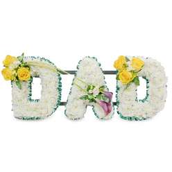 A comforting, bespoke funeral tribute that spells 'DAD' in bold, freestanding capital letters, each letter densely covered with pristine white chrysanthemums to create a soft, cloud-like surface. The letters are edged precisely with a ruffled deep-green satin ribbon, which reads like a dark, elegant frame against the pure white flowers, while slim dark-green metal bars behind the letters connect and support them so they stand as a united statement of remembrance. On the upper left curve of the first 'D' a bright cluster of warm yellow roses-three or four in full face-nestles with small white filler blooms, perhaps freesias or gypsophila, and strips of fresh greenery; two long, slender green stems extend diagonally across toward the center, adding motion and a quiet grace.

At the base of the 'A' a refined cluster of two deep purple calla lilies makes a solemn focal point, their smooth trumpet shapes offering an air of reverence; they are surrounded by subtle white accents and glossy foliage that soften the tone. The right 'D' mirrors the left, repeating the cheerful yellow rose clusters and tying the design together with visual reassurance. The piece is photographed against a plain white backdrop in soft, even light so texture and color read clearly; the scent suggests clean chrysanthemums and a hint of rose. Prepared by Flower Delivery Queensbury for local memorials and sympathy services, this arrangement carries dignity, clarity and a carefully chosen palette intended to comfort family and friends across Queensbury, Kingsbury and Wembley.
