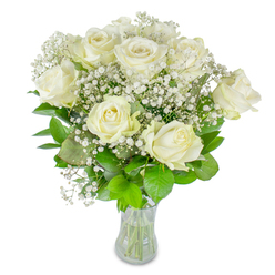 A serene, classic bouquet of roughly twelve pristine white roses sits in a plain clear glass vase, the trimmed stems visible through the water as a quiet assurance of freshness. Each rose unfurls with creamy, satiny petals-some fully open and glowing, others still forming delicate spirals-so the arrangement breathes with natural rhythm. Tiny clusters of baby's breath (Gypsophila) weave between the larger blooms like sifted snow, lending an ethereal, airy texture that softens the roses' form and adds a romantic halo. The greenery beneath ranges from cool, deep green to lime-tinted leaves, glossy and structured, providing a verdant frame that makes the whites sing against the bright white background. Gentle, diffused light highlights the faint ivory blush at petal edges and suggests a subtle, clean fragrance that reads as tender rather than overpowering. As a local florist in Queensbury, I often arrange this composition for weddings, milestone anniversaries, or as a dignified sympathy offering to bring calm to a room; it's the kind of bouquet people ask for when they want purity and grace. Flower Delivery Queensbury prepares and dispatches stems like these with careful stem-conditioning and neat presentation, suitable for same-day local delivery around Queensbury Station, Kingsbury, and neighbouring Canons Park when timing is important. The overall impression is of timeless simplicity and considered craft: each stem chosen, trimmed, and placed to create a quiet, radiant statement of affection and respect.