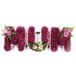 The image shows a beautifully composed "MUM" funeral tribute, its three bold letters carefully formed from individual floral frames and presented against a clean, white studio-style background so every detail is visible. Each letter is densely massed with small, button-like chrysanthemums in jewel tones of deep magenta and purple, their petals creating a plush, almost velour texture. Tiny lime-green centres punctuate the surface like scattered stars, giving a lively sparkle that stops the darker hues from feeling heavy. Around the outside of each letter, a pale, ruffled pink ribbon is neatly pinned, the soft frill echoing the gentle nature of a mother's touch and giving the pieces crisp definition. The top-left shoulder of the first "M" is graced by a tasteful cluster of hot pink roses, some fully open, others in tight bud, nestled among arching fern fronds and glossy greenery. At the base of the central "U", a more pastel grouping of blush and cream roses, delicate white flowers, and mixed foliage forms a low, rounded embellishment, like a small posy placed lovingly at the feet of the letter. On the top-right of the final "M", another matching spray of bright pink roses and fern leaves completes the symmetry, visually cradling the word from either side. The tribute carries a quiet elegance and emotional weight, the textured flowers and soft pink ribbons suggesting tenderness and cherished memories. It is the sort of thoughtfully crafted memorial piece ordered for services in and around Queensbury, perhaps for a farewell at a nearby church or cemetery, where the colour and form can gently comfort family and friends.