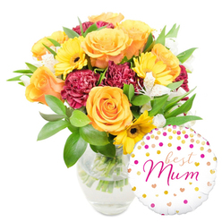 This arrangement reads like a neighbourhood love letter - a bouquet shaped to make a mother smile, pictured here against a crisp white background. At its heart sit large orange and warm peach roses, their petals unfurling in soft spirals that catch light and suggest a delicate, sweet fragrance. Scattered among them are vibrant yellow gerbera daisies whose flat, sunny faces and dark centres add immediate cheer, while clusters of deep burgundy carnations introduce a velvety, romantic contrast with densely ruffled petals. Thin sprays of white alstroemeria, flecked with subtle speckles, lend an aristocratic lightness that balances the bolder blooms. Lush, varied green foliage - glossy broad leaves and feathery stems - cushions the flowers and gives the bouquet a freshly gathered-from-the-greenhouse feel. All stems sit in a simple clear glass vase; the waterline and trimmed green stems are visible, underscoring freshness and careful workmanship. Nestled to the bottom right and playfully overlapping the vase is a round white foil balloon decorated with scattered gold and hot-pink confetti dots and tiny hearts, the centre proclaiming "best Mum" in flowing hot-pink script - a personal message that completes the gift. Prepared with the careful eye of a local shop familiar with Queensbury's community, this style of bouquet is ideal for Mother's Day or a heartfelt birthday surprise, and is available for local delivery across Queensbury and neighbouring Kingsbury and Wembley by Flower Delivery Queensbury.