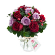 A lush, rounded bouquet of roses that reads like a quiet love letter in colour and texture: deep, velvety crimson and burgundy blooms sit almost evenly with soft lavender and dusty purple roses, each flower fully open with gently unfurling petals. Dark green foliage-think Ruscus or Salal-frames and cushions the heads, its glossy leaves pushing the rose tones forward while adding a cool, earthy backdrop. Scattered between the blooms are small, bright red-orange rose hips that introduce a rustic, tactile contrast; their firm, satiny skins catch the light against the velvet of the petals and give the arrangement a seasonal, hand-gathered feeling. The stems are gathered into a rounded silhouette and presented in a reflective mercury-effect glass vase with an antique silvered finish: the glass is bulbous at the base and tapers slightly at the neck, the mottled surface shimmering and throwing soft highlights across the petals. A natural raffia tie is knotted around the neck and a rectangular white gift tag hangs forward, marked with a simple floral sketch and space for a handwritten note rather than a brand logo. The composition sits on a brilliant white background, the clarity of the setting making each shade read true and clean - the cool mauves glow, the reds deepen, and the greens remain vivid. Sensory details linger: the satiny touch of petals, the firmer texture of hips, the faint perfume of roses; the whole piece feels considered and romantic, perfect for anniversaries, intimate congratulations, or as a premium bouquet sent to brighten a home in Queensbury, Canons Park or nearby Kingsbury.