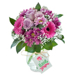 A lavish, rounded bouquet brimming with fuchsia pink, magenta, and soft lavender hues glows in a textured glass vase, captured in bright, even light. The arrangement's cheerful spirit shines through its lively Gerbera daisies, their hot pink petals and distinctive dark centers reflecting the exuberance of celebrations along Kenton Road. Delicate lavender roses, gently opening, rest amidst the display, their soft tones perfectly complemented by rich, plum-coloured chrysanthemums. Wisps of pure white baby's breath scatter throughout the bouquet, creating an ethereal effect and balancing the intensity of the bold blooms. Around the perimeter, glossy deep green foliage unfurls, giving structure and a fresh, garden-picked feeling. The vase, with its delicate crackled finish, is tied with rustic, pale raffia and adorned with a minimalist white gift tag, suggesting possibilities for personalised messages. This bouquet's vibrant palette and careful arrangement evoke joy, appreciation, and the subtle elegance found in Queensbury homes. Perfect for birthdays, heartfelt thank-yous, or simply bringing a touch of outdoors inside, it embodies the artistry of local florists who understand what it means to celebrate life's meaningful moments in the heart of northwest London.