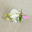 An elegant boutonniere lies on a softly woven, oatmeal-coloured linen cloth, the natural fabric adding warmth and texture to the composition. In the centre, a single white Phalaenopsis orchid takes pride of place, its velvety petals wide and gently curved, as if caught mid-unfurl. The flower's throat carries a delicate glow of yellow-orange with a suggestion of pink, giving depth and character to the otherwise pristine bloom. Around it, a generous ring of delicate baby's breath creates an airy, cloud-like effect, each tiny white Gypsophila flower catching the light and softening the edges of the design. Slender green foliage, polished and fresh, slips in and out from behind the petals, providing clean lines and a vibrant contrast to the cream and white tones. To the side, three rounded orchid buds in pale green cluster together on a single stem, their closed forms hinting at flowers soon to open, adding a quiet sense of movement and growth. The base of the piece is wrapped in bright pink satin ribbon, smoothed tightly around the stems and finished with a neat bow whose short tails rest lightly on the cloth. The satin's sheen lends a playful, modern note to this otherwise classic buttonhole, perfect for a wedding ceremony at a local Queensbury venue or a smart prom outfit. Crafted with the care you'd expect from a florist who knows the pace and style of Queensbury life, the design feels intimate, refined, and ready to be pinned close to the heart.