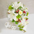 A refined white and green centerpiece sits calmly on a spotless white surface, its gentle elegance perfectly suited to a wedding breakfast in Queensbury or an intimate reception near the local parks. The bouquet is composed around several impressive white Oriental lilies, their satin petals open wide, showing off fine freckles and rich, rust-colored stamens. Tucked close by is a single, perfectly spiraled yellow rose, its creamy golden heart adding warmth and a soft focal glow. Throughout the arrangement, airy sprays of white baby's breath weave between the larger blooms, forming a cloud-like backdrop that softens every edge. Almost spherical, bright green Green Trick dianthus stand out like little moss cushions, their unusual, fuzzy texture echoed by the feathery, light-green foliage that fans out to create depth. Cherry-red hypericum berries gleam among the greenery, catching the light and bringing a joyful, festive spark to the otherwise tranquil palette. On the right-hand side, a trail of pristine white Phalaenopsis orchids cascades gracefully downward, each bloom pristine and sculptural, with a hint of yellow at the throat and smooth green buds promising more flowers to come. The bouquet is anchored in a white woven basket that barely peeks through the profusion of petals, its texture thoughtfully mirrored by two white wicker spheres resting on the table. The soft beige background and gentle lighting frame the arrangement like a studio portrait, making it easy to imagine this piece as a luxury wedding bouquet, a top-table centerpiece, or a refined floral arrangement delivered fresh to Queensbury venues and family homes for milestone celebrations.