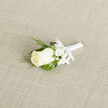 This wedding boutonnière appears as a small work of art laid carefully on a pale, textured cloth, every element balanced with intention. At its centre is a creamy ivory rose, the bloom open enough to reveal its layered heart while still holding the softness of a fresh morning flower. Its petals, smooth and velvety, seem to catch the light with a subtle satin glow. Around the rose, sprigs of baby's breath form a filigree of tiny white blossoms, their cloud-like clusters blurring the line between flower and air. Slender strands of ornamental grass curl and weave around the central bloom, their rich green colour providing a striking contrast to the ivory tones and adding a sense of natural movement, as though a breeze from nearby Queensbury Park had just brushed past. The stems are neatly wrapped in sleek white satin ribbon, wound tightly to create a polished handle that fits comfortably in the hand before being pinned to a lapel. The ribbon's slight sheen echoes the sophistication of formal wedding attire, while the tiny, precise bow at the base underscores the florist's care and craftsmanship. The neutral fabric beneath, with its gentle woven pattern, provides a calm backdrop that lets the boutonnière's gentle colours and textures shine. You can almost imagine the cool touch of the petals and the faint, clean fragrance that follows someone walking into a ceremony in Queensbury, carrying with them this quiet yet meaningful floral accent for a groom, best man, or beloved guest.