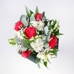 A hand-tied bouquet overflowing with crimson roses, pink-red carnations, and soft white daisies rests against a neutral background, glowing as if in gentle Queensbury morning light. The red roses are full and velvety, their petals spiralling inward with a rich, romantic intensity, while the carnations beside them ruffle into feathery folds of magenta and scarlet. Clusters of tiny snow-white chrysanthemums and daisies brighten the arrangement, their sunny centres echoing the feel of a clear day over Queensbury Park. Wisps of gypsophila, or baby's breath, drift between the larger flowers like a delicate cloud, softening every edge. Eucalyptus stems arch through the bouquet, their muted green and silvery-blue leaves adding a cool, contemporary touch, balanced by deep tropical foliage that frames the flowers in glossy, dark green. The bouquet is tightly yet thoughtfully composed, domed and rounded without feeling stiff, each bloom given room to breathe and be noticed. One can almost sense the quiet rustle of leaves and the light, mixed fragrance of rose, carnation, and fresh greenery, like stepping into a well-loved local flower shop after a walk along Queensbury's high street. This is the kind of arrangement you might place at the centre of a birthday table, carry to a reunion, or set on a hallway console to greet someone coming home. It feels like a bouquet designed to mark fresh starts and heartfelt congratulations, crafted with the steady, practised hands of a florist who understands both the drama of bold colour and the calming balance of white and green.
