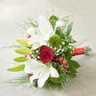 A refined wedding-style bouquet is displayed on a neutral, woven light-cream surface, the understated background allowing every flower to shine as if arranged for an elegant celebration in Queensbury. Dominating the composition, open white oriental lilies stretch their wide petals outward, each bloom luminous and gently ruffled, dusted with subtle reddish freckles at the throat. Alongside them, several green lily buds remain tightly wrapped, promising fresh waves of fragrance over the coming days. Near the centre rests a single deep red rose, its petals velvety and perfectly spiralled, creating a focal point of classic romance that would suit a proposal dinner near Queensbury Station or an intimate registry-office wedding. Flanking these key flowers are two round tufts of bright 'Green Trick' dianthus, their fuzzy, almost moss-like texture adding an intriguing contrast to the smooth lilies and rose. Fine sprigs of delicate baby's breath weave between the larger blooms, appearing like tiny white stars suspended in mid-air. Scattered clusters of shiny red hypericum berries repeat the rich scarlet tones, lending the bouquet a warm, festive character. A variety of fresh greenery fans outward, from broad glossy leaves to slender, grass-like blades that arc gracefully across the pale fabric, giving the bouquet a sense of natural movement and fullness. The stems are tightly bound with a wide, shimmering red satin ribbon, which lies diagonally at the base and suggests thoughtful craftsmanship. Soft, natural light washes over the arrangement, casting gentle shadows that highlight each curve and texture, making this bouquet feel perfectly suited to Queensbury wedding photos, anniversary surprises, or romantic same-day flower delivery.