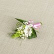 A delicately handcrafted boutonniere rests on a softly textured, light beige fabric that looks like natural linen, its neutral tone allowing every flower to stand out with clarity and grace. At the heart of the piece is a single pristine white alstroemeria bloom, its broad petals gently flared open to reveal fine reddish-brown speckles gathered near the throat, like careful brushstrokes. The petals appear slightly ruffled at the edges, giving the flower a soft, almost papery texture, while the stamens sit clearly in the centre, dusted with pale pollen. To the left, a striking lime-green conical cluster of tightly packed buds, reminiscent of Ornithogalum, adds height and structure, each bud forming a small scale-like facet that catches the even, natural light. Feather-light sprigs of white baby's breath weave around the main blooms, their tiny blossoms floating like a cloud and softening every edge. Dark green, sword-shaped foliage forms a solid background, while finer, grass-like strands arc gently outward, adding movement and a touch of wild garden charm. At the right, a neat bow of glossy pink satin ribbon secures the stems, its cheerful colour suggesting celebration and romance. The overall composition, calm and balanced, feels perfect for a wedding morning in Queensbury, perhaps pinned to a lapel before a ceremony at a local church or registry office, a small, intimate accent that speaks of freshness, care, and thoughtful local floristry.