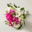 A vibrant Queensbury-inspired wedding bouquet bursts with luxurious fuchsia peonies and ethereal white Alstroemeria, their petals finely streaked with reddish lines that capture intricate detail. The arrangement gleams with a lively contrast between the plush, ruffled peonies and the airy, star-like lilies, all enhanced by fresh, spiky green florets reminiscent of springtime in local parks. Sprays of creamy bell-shaped flowers offer a gentle, romantic softness, highlighted by deep green foliage that adds depth and richness, as if plucked fresh from a Queensbury morning. Neatly bound with a gleaming pink satin ribbon, the hand-tied bouquet radiates love and artistry, poised on an understated beige fabric that accentuates the floral drama. The ensemble feels both intimate and exuberant, evoking celebrations held in nearby community venues or exchanges of vows in local gardens. Every aspect, from colour interplay to the tactile mix of petals and leaves, reflects the skill and care of a true Queensbury florist, making this bouquet an ideal symbol of romance, joyful occasions, or new beginnings within the area.