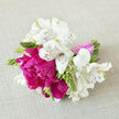 A finely crafted hand-tied bouquet lies against a textured, neutral cloth, its colours and textures echoing the soft, calm light of a Queensbury afternoon. Snowy alstroemeria, each bloom marked with delicate maroon brushstrokes, create a refined outer ring, bringing a sense of purity and tradition to the design. At the core, lush peonies in bright fuchsia and deep raspberry pink bloom in ruffled layers, their petals overlapping like crumpled silk, infusing the arrangement with joy and a hint of drama. Firm green buds and slim stems weave between the larger flowers, offering structure and a promise that more beauty is still unfolding. The bouquet is bound low on the stems with a smooth, satiny pink ribbon, neatly tied yet relaxed enough to feel personal and hand-gathered rather than rigid. Soft shadows fall under each flower head, emphasising the depth and roundness of the posy as it rests on the fabric, as though it has just been set down on a table in a Queensbury living room for a quiet moment of admiration. The imagined scent is gentle and fresh, like a small garden off Church Lane after a light shower - subtly sweet, green, and uplifting without being overpowering. This composition would make a tender bridesmaid bouquet for a local ceremony, a romantic anniversary gift delivered across Queensbury and the surrounding streets, or a heartfelt thank-you for someone who loves modern florals with a classic twist. Every detail speaks of care, gratitude, and the soft optimism that flowers bring.