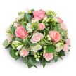 A soft, domed cushion of blooms arranged with a florist's calm hand, this compact tribute brings together blush-pink roses and pristine white freesia against a clean white backdrop. The composition is densely packed so no stems show-large, fully opened roses reveal velvety spirals of petals in shades from pale blush to a gentle salmon, while smaller spray roses and tight buds add layered texture and a sense of depth. Clusters of pure white freesia stand upright between the roses; some bells are fully open and reveal tiny yellow stamens, others remain as pencil-like buds promising more perfume and life. Glossy, dark green foliage forms a rich foundation, likely ruscus or salal, while variegated leaves edged in creamy white-reminiscent of pittosporum-catch the light and lend a delicate contrast. The petals look soft and dewy, the freesias offering a faint, citrus-honey scent that lifts the arrangement's quiet mood. Soft natural light from above sculpts a subtle shadow beneath the rounded silhouette, making the rose tones and white blooms feel tranquil and refined. A bouquet of this style speaks gently of comfort and remembrance: ideal as a sympathy tribute, a memorial display, or a composed gift for a calm celebration such as the arrival of a new baby or a thoughtful anniversary. As a local florist familiar with Queensbury's quieter mornings near the tube and neighbourhood parks, I picture this arrangement delivered with care across the area, filling rooms with a serene colour palette and the reassuring softness of freshly cut roses and freesia.