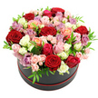 A sophisticated round hat box arrangement of roses sits centre-stage in this photograph, styled in a perfect dome that seems to brim just to the edge of the box. The container itself is a deep matte black, trimmed neatly with a red band around the base that echoes the most intense tones in the flowers. Against the pure white background, the colours of the roses appear exceptionally vivid and true. At the heart of the design are velvety red roses, rich and romantic, surrounded by an ever-changing halo of hues: soft blush pinks, dusky rose, bright fuchsia, creamy whites, cool ivory, warm peach and coral, and gentle lavender and mauve. Some blooms are wide open, their layered petals curling outward like silk, while others remain in tighter, rounded forms or appear as smaller spray roses, tucked in like little secrets between their larger neighbours. Bright, glossy green leaves weave in and out of the flowers, breaking up the colour and giving the bouquet a fresh, living vibrancy rather than a static, posed feel. The light is even and soft, with no harsh shadows, allowing every detail of the petals and foliage to be seen clearly. This arrangement has the quiet glamour of a premium floral gift crafted for a special moment in Queensbury-perhaps a romantic surprise delivered to a flat near Queensbury Station, a congratulatory gesture for new homeowners off Kingsbury Road, or an elegant centrepiece for an intimate celebration where roses are meant to convey love, admiration, and deep appreciation without saying a word.
