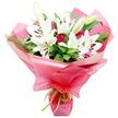 A carefully arranged bouquet of white Oriental lilies and red roses fills this image with an air of polished romance and celebration. The lilies rise prominently at the centre, their large trumpet blooms fully open in places, revealing soft white petals that sweep outward like wings and frame a cluster of chocolate-brown stamens dusted with pollen. Some lilies remain partially closed, held in elongated buds streaked with green and cream, adding height and a sense of unfolding time. Interwoven with the lilies are numerous red roses, mostly in compact buds or half-open forms, their densely layered petals creating deep, velvety spirals of colour that draw the eye inward. The flowers emerge from a lush foundation of dark green leaves-broad, shiny foliage mixed with finer, spike-like greenery that adds structure and texture to the design, much like the varied plantings in front gardens along the streets between Queensbury and nearby Kingsbury. The entire arrangement is cradled in a wide swathe of bright pink, glossy cellophane or floral paper, its translucent layers gathered and ruffled so that they billow around the stems. The wrapping reflects light in subtle highlights, making the bouquet appear even more vibrant and festive. A slender lime green ribbon is neatly tied around the base, introducing a final fresh note of colour that complements the leaves and adds a professional finishing touch. This bouquet would feel perfectly suited to a joyful birthday surprise, an anniversary delivered to a home near Queensbury Underground, or a heartfelt thank-you sent across the local neighbourhood.