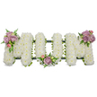 A solemn, lovingly prepared funeral tribute spells the word MUM in bold capital letters, each letter built up from thousands of small, snow-white chrysanthemums packed tightly to form a soft, cloud-like surface. Against a clean white backdrop the arrangement reads as both a visual and tactile expression of calm; the chrysanthemums give a gentle, downy texture while their cool, bright white suggests purity and quiet dignity. Three delicate clusters of muted lilac and pale pink roses rest like careful notes of colour: one nestles on the upper left arm of the first M, another settles in the gentle curve of the U, and a final cluster adorns the upper right arm of the last M. Fresh green foliage - slender fern fronds and small glossy leaves - weaves among the roses, offering contrast and a sense of depth while a darker green support frame peeks beneath the blooms, a subtle line that holds the letters together. There is a faint scent of roses that softens the sharper, green edge of the foliage, and soft studio light from above highlights the layered petals and the three-dimensional sculpting of each letter. This is a sympathetic, traditional tribute meant to comfort and commemorate, chosen to honour a mother's memory at a funeral service, wake, or graveside. As a local florist who knows Queensbury and nearby Kingsbury and Fryent Country Park, I picture this arrangement arriving respectfully at a chapel near Queensbury Station, carrying the hush of remembrance and a quiet, graceful beauty that helps family and friends remember with love.