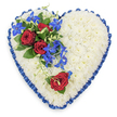A large, heart-shaped floral tribute fills the photograph, its outline crisp against a plain white background that draws all attention to the careful craftsmanship. The heart's interior is completely covered with tightly massed white chrysanthemums, their small, rounded petals overlapping to form a dense, plush texture reminiscent of soft snow or a padded quilt. This unbroken expanse of white sets a soothing, contemplative tone. Running around the entire perimeter of the heart is a royal blue satin ribbon, intricately pleated and ruffled by hand. The ribbon's glossy surface catches highlights and shadows, creating a gentle shimmer that accentuates each curve of the heart and adds a sense of ceremony. On the upper left side, a dramatic arrangement of flowers forms the focal point: three fully opened deep red roses with velvety, spiralling petals nestle amongst dark, polished green leaves. From within this cluster, electric blue dendrobium orchids spill out and cascade downward, their elongated stems and star-shaped blooms creating a flowing diagonal movement. The orchids' intense blue, tinged with hints of teal and purple, stands out vividly against the white chrysanthemum base. Fine light green curly tendrils curl and twist around the roses and orchids, adding delicate, natural lines that soften the composition. On the lower right curve of the heart, a single, equally rich red rose lies on its own, echoing the main cluster and balancing the design with quiet simplicity. The overall effect is one of heartfelt condolence and dignified love, the kind of floral tribute a family in Queensbury might choose to honour someone dear at a funeral or memorial service, expressing purity, devotion, and calm remembrance in a single, tender gesture.