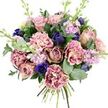 This photograph shows a generous, hand-tied bouquet resting against a pure white background, every colour and texture standing out as if illuminated by soft daylight in a Queensbury florist's window. At its centre, open garden roses in shades of blush pink, dusty mauve, and antique rose create a sense of gentle romance, their velvety petals spiralling inward in intricate, layered whorls. Around them, lavish carnations with finely ruffled edges provide volume and movement; their petals shift from creamy beige and soft blush at the core to deeper rose and plum tones at the fringes, giving the bouquet a nostalgic, almost vintage character. Threaded carefully through these warm hues, rich blue and indigo flowers add depth and drama, some appearing as slender, tulip-like buds, while a single, fully open royal blue anemone with a nearly black centre holds a place of prominence near the lower front, like a gemstone in a setting. Slender spikes of lilac and pale lavender stock rise gently above the main body, each stem carrying many small blossoms that lighten the arrangement and hint at a soft, sweet fragrance, reminiscent of gardens around nearby parks and residential streets. Embracing the blooms, a mix of dark, glossy leaves and cool, silvery eucalyptus discs creates a refreshing green frame, their shapes overlapping to form a natural, flowing outline. The stems are visible and neatly tied, emphasising the bouquet's hand-crafted nature and readiness for gifting. With its blend of soothing pinks and purples offset by striking blues, this design feels quietly luxurious and deeply comforting, suited to anniversaries, heartfelt thank-yous, or moments when you want to bring a touch of beauty into someone's Queensbury home.